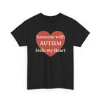 Black t-shirt printed with a large salmon-red heart made of jigsaw puzzle pieces, lettered across it "Someone with AUTISM Stole my Heart", shown flat from another angle.
