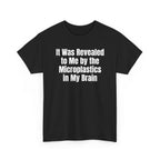 Black t-shirt printed with "It was revealed to me by the microplastics in my brain", shown flat from another angle.