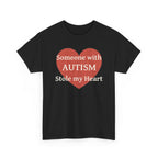 Black t-shirt printed with a large salmon-red heart made of jigsaw puzzle pieces, lettered across it "Someone with AUTISM Stole my Heart", shown flat from another angle.